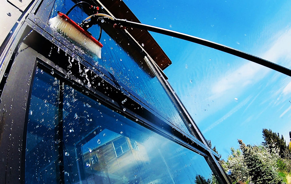 A staff member pressure washes a brick driveway removing dirt and grime.